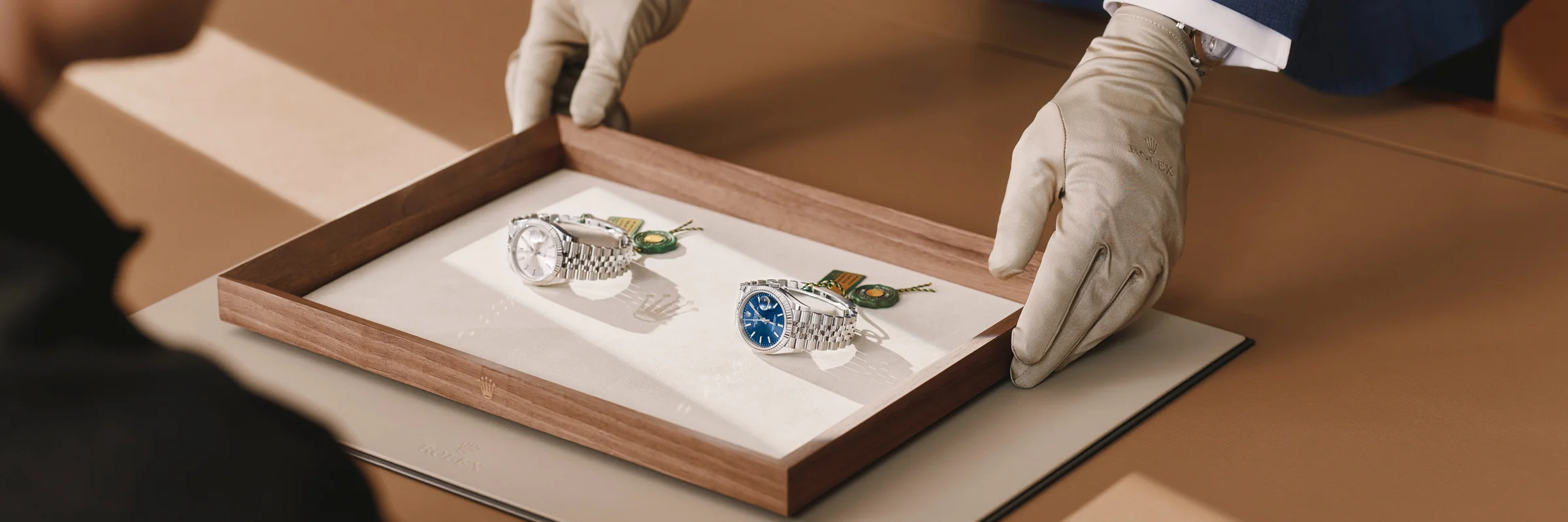 Gloved man holding a Rolex watch for a customer to view